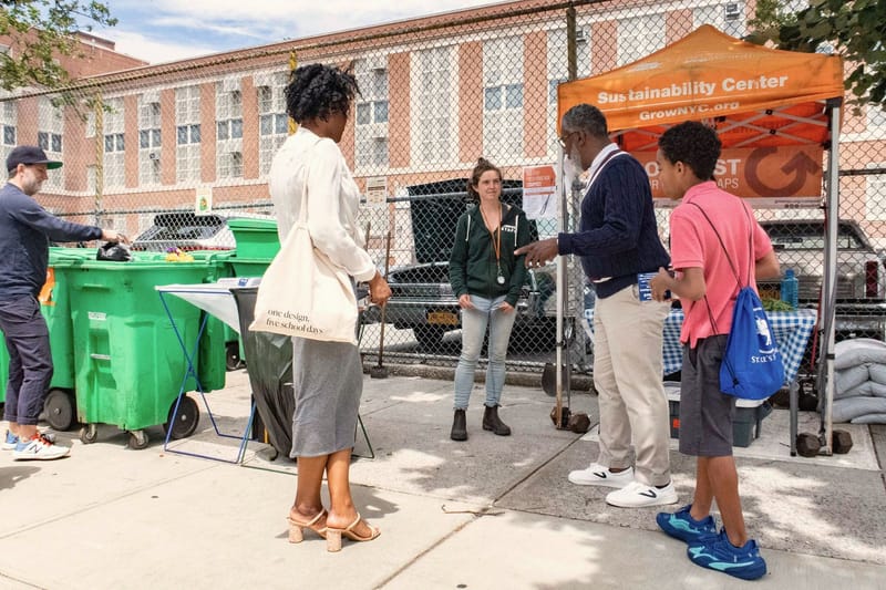 Neighbors stand and talk together beside an outdoor information tent.